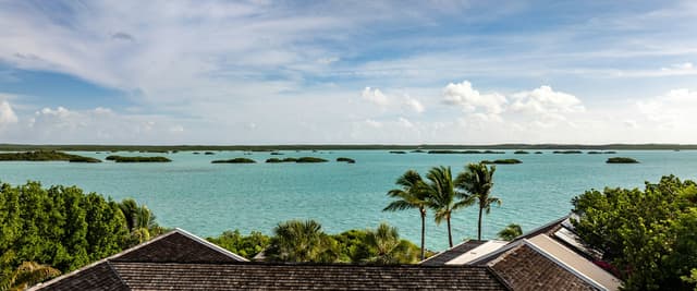 Rooftop view over turquoise water with palm trees and small islands in the distance