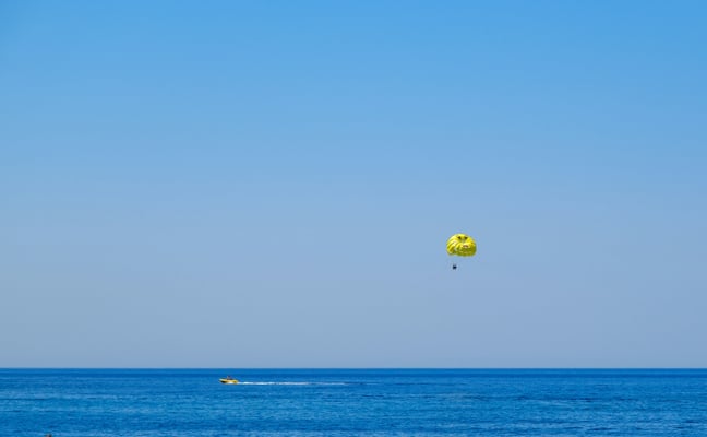 Yellow parasail soaring over calm blue ocean water