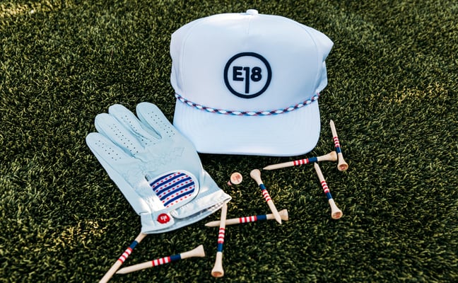 Golf hat, glove and tees laid out on grass