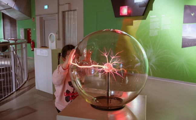 Child touching plasma ball at science exhibit