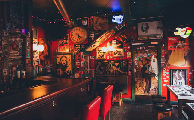 Irish pub interior covered in memorabilia and posters with a warm red glow