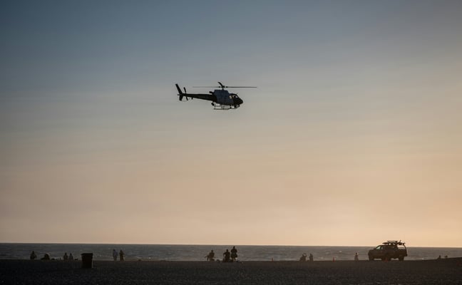 Helicopter flying low over the beach at sunset
